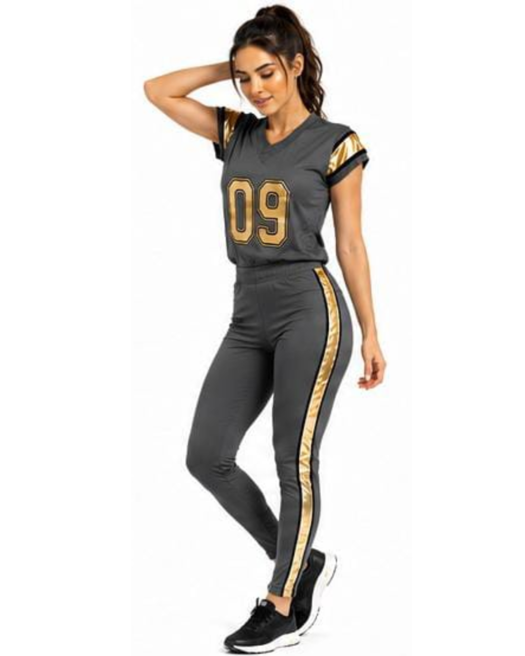 A woman modeling a dark gray athletic tracksuit with gold accents, featuring a short-sleeve jersey top with the number '09' on the front and matching side stripes, paired with high-waisted leggings and black sneakers.