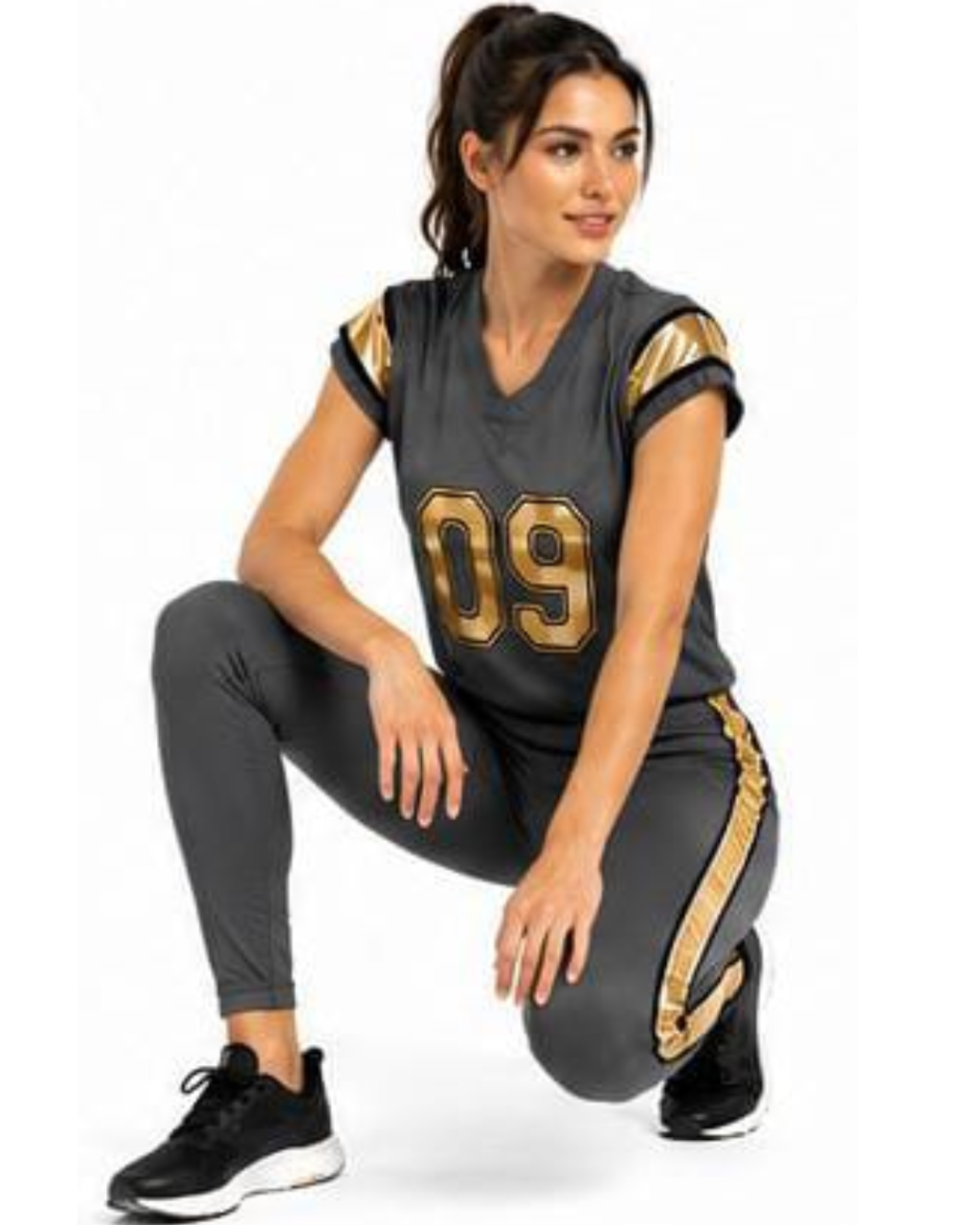 A woman crouching in a dark gray athletic uniform set with gold accents, featuring a V-neck jersey with '09' on the front and matching leggings, paired with black sneakers, against a plain white background.