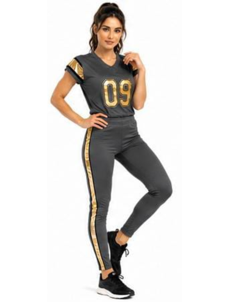 A woman modeling a dark gray athletic set consisting of a short-sleeve V-neck jersey top with gold trim and the number '09' on the chest, paired with matching dark gray leggings featuring a gold side stripe.