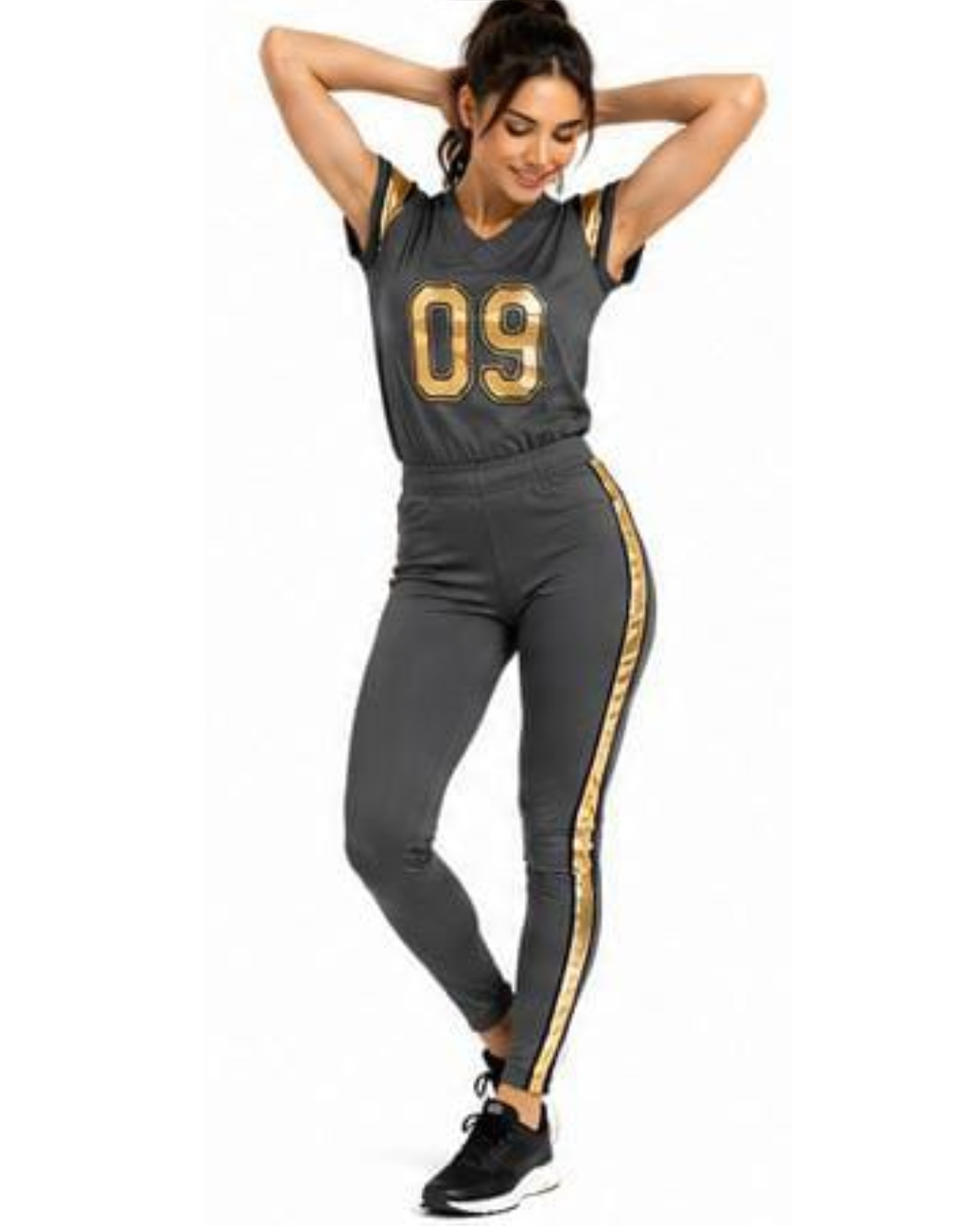 A woman modeling a dark gray athletic two-piece set featuring a short-sleeve jersey top with gold trim and the number '09' on the front, paired with matching dark gray leggings that have a gold stripe down the side.