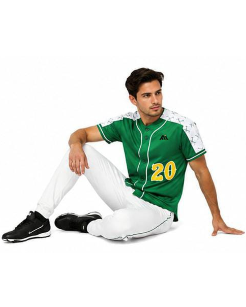 A man wearing a green baseball-style jersey with white sleeves, white pants, and black sneakers, sitting against a plain white background.