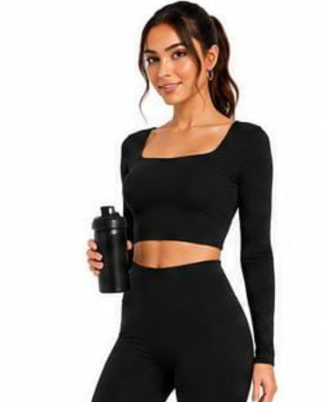 A woman modeling a black long-sleeve crop top and matching high-waisted leggings, holding a black shaker bottle against a plain white background.