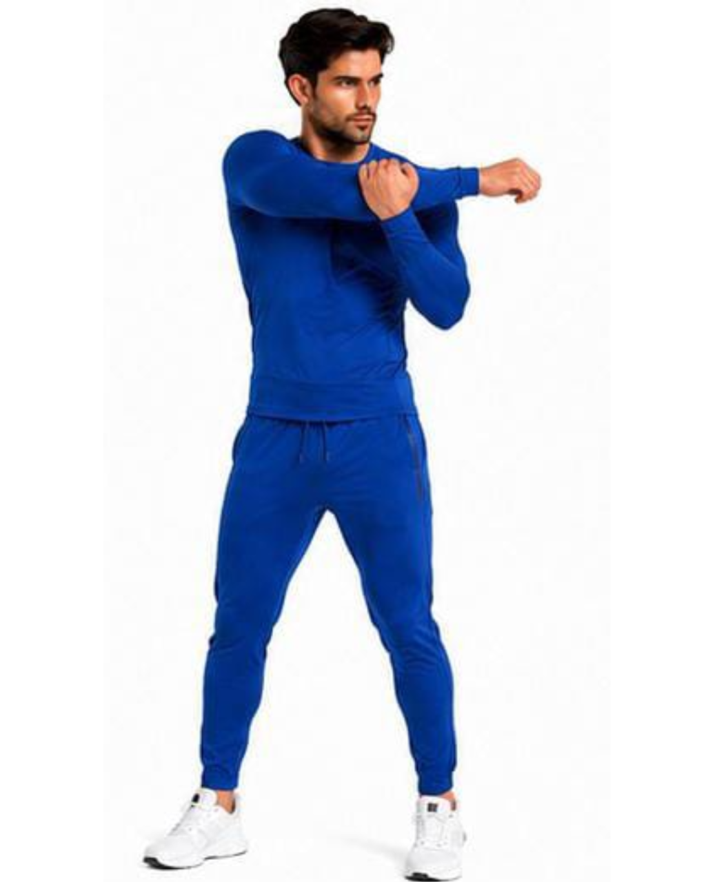 A man modeling a royal blue two-piece tracksuit consisting of a long-sleeve top and matching jogger pants, paired with white sneakers, against a plain white background.