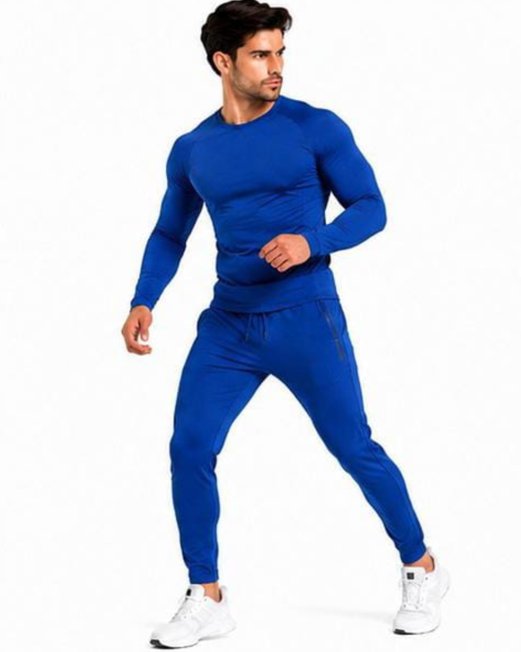 A man modeling a matching royal blue long-sleeve athletic top and jogger pants set, paired with white sneakers, against a plain white background.