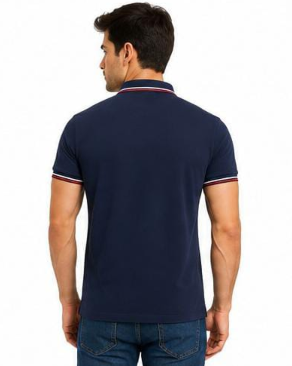 A man viewed from the back wearing a navy blue short-sleeve polo shirt with white and red striped trim on the collar and sleeve cuffs, paired with blue jeans against a plain white background.