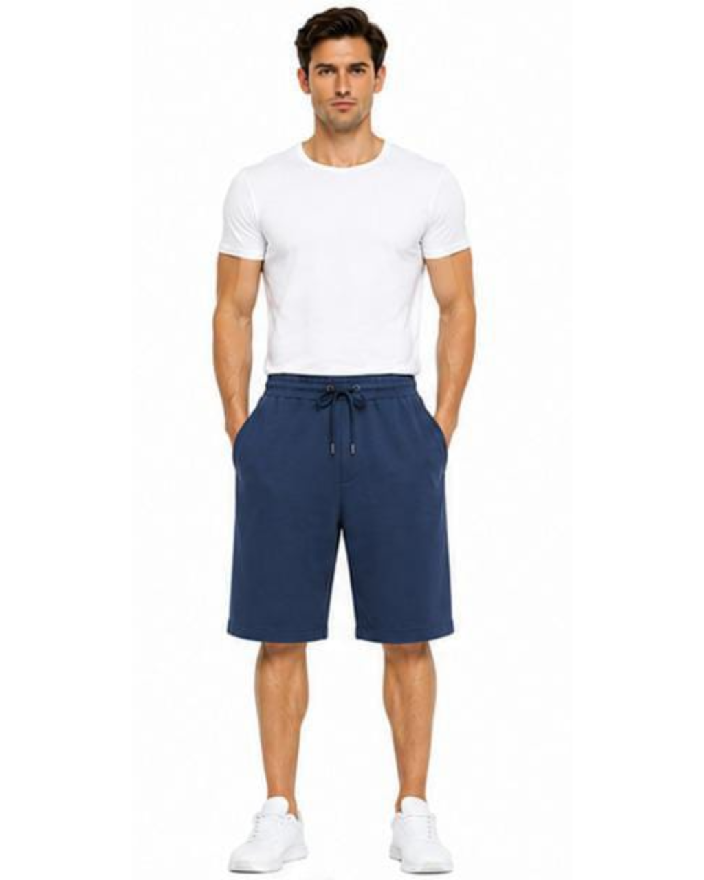 A man modeling a pair of navy blue drawstring shorts with a white t-shirt and white sneakers, standing against a plain white background.