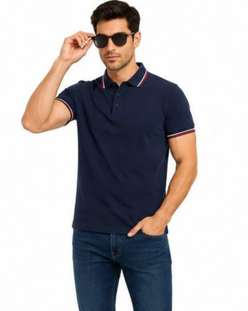 A man wearing a navy blue short-sleeve polo shirt with red and white striped trim on the collar and sleeve cuffs, paired with dark blue jeans and black sunglasses, against a plain white background.