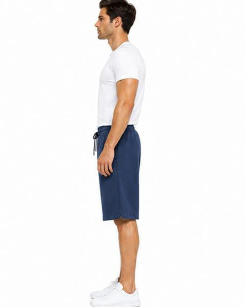A man shown in profile wearing a white short-sleeve t-shirt, navy blue drawstring shorts, and white sneakers against a plain white background.
