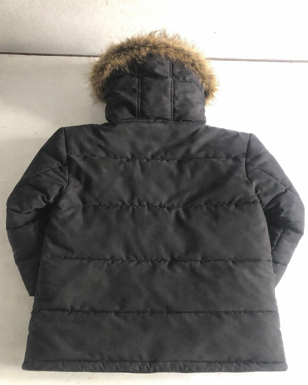 Black winter coat with fur hood on a light background