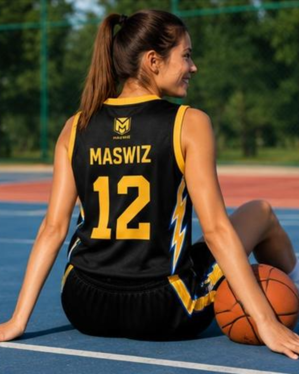 Woman sitting on a basketball court wearing a black jersey with 'MASWIZ' and number '12'.