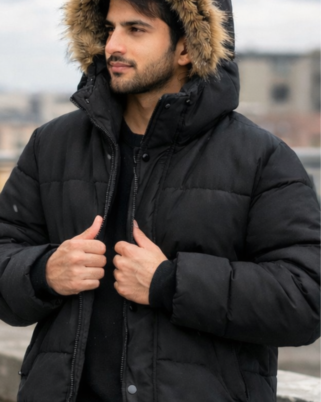 Man wearing a black puffer jacket with a fur-lined hood outdoors.