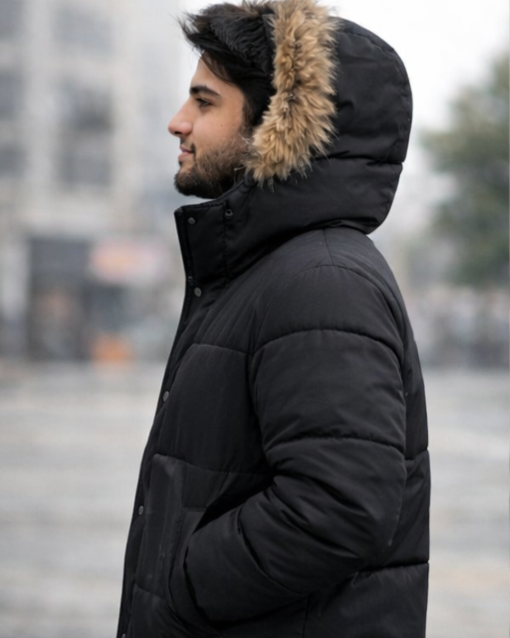 Man wearing a black winter coat with fur-lined hood in an urban setting