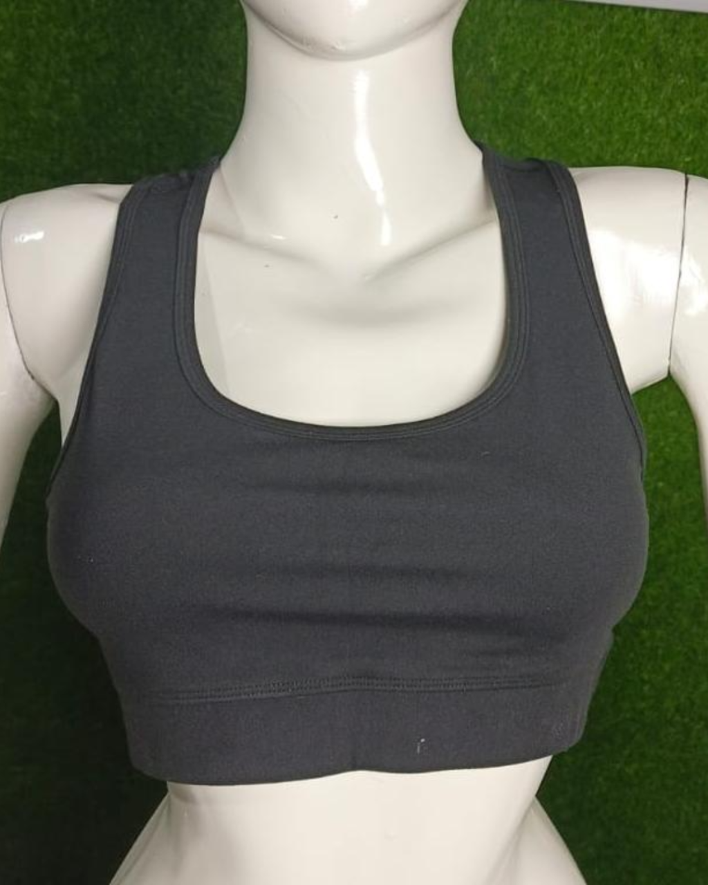 Black sports bra on a mannequin against a green grass background
