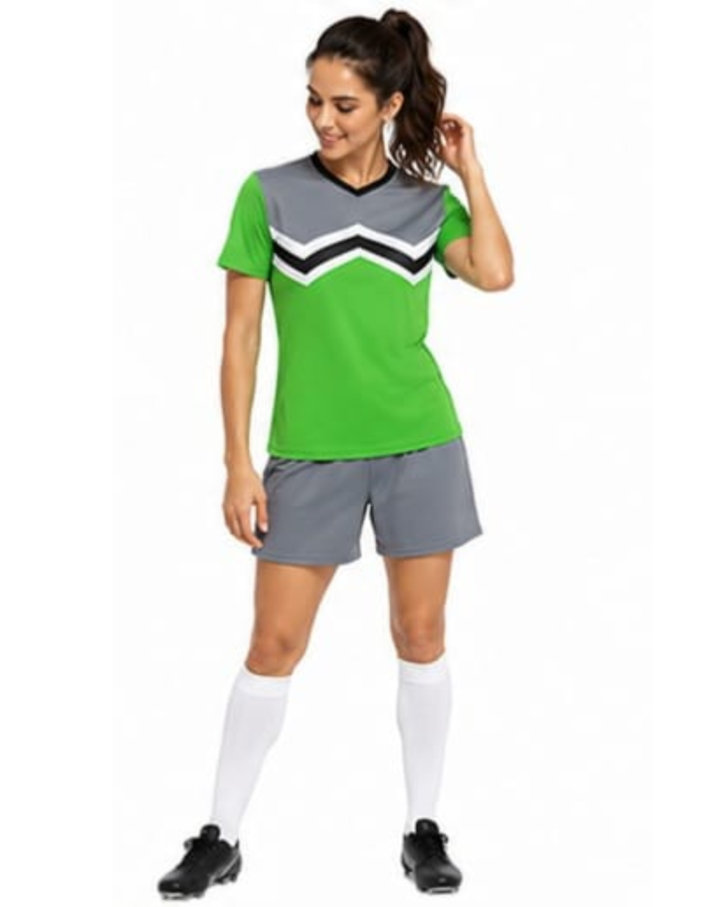 A woman modeling a short-sleeve athletic soccer jersey and matching shorts set. The jersey is bright green with a gray yoke and a black and white chevron pattern across the chest.