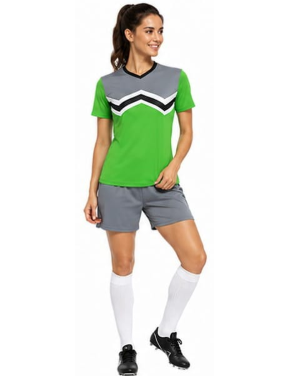 A woman modeling a bright green and gray athletic soccer jersey with a black and white chevron pattern on the chest, paired with gray shorts, white knee-high socks, and black cleats, set against a plain white background.
