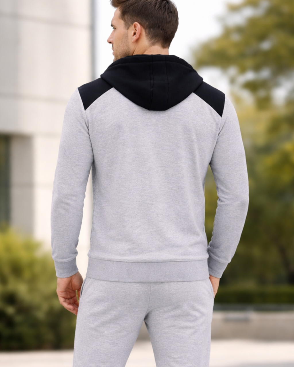 Man wearing a gray and black hoodie with matching pants outdoors.