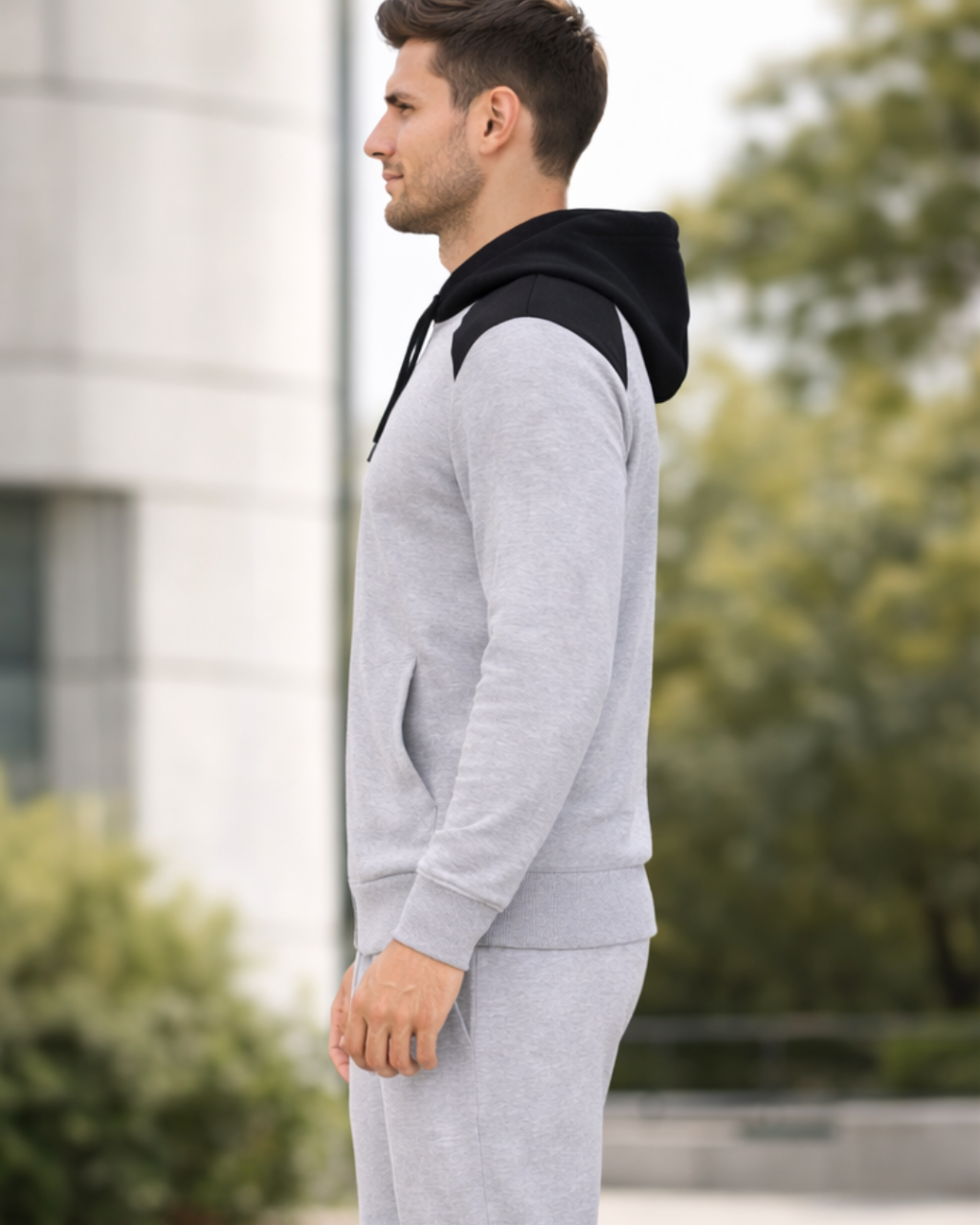 Man wearing a gray tracksuit with a black hood in an outdoor setting