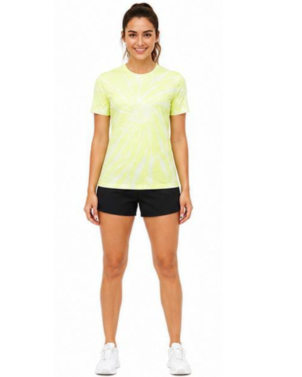 A woman modeling a neon yellow-green and white tie-dye short-sleeve athletic t-shirt with black athletic shorts and white sneakers, standing against a plain white background.