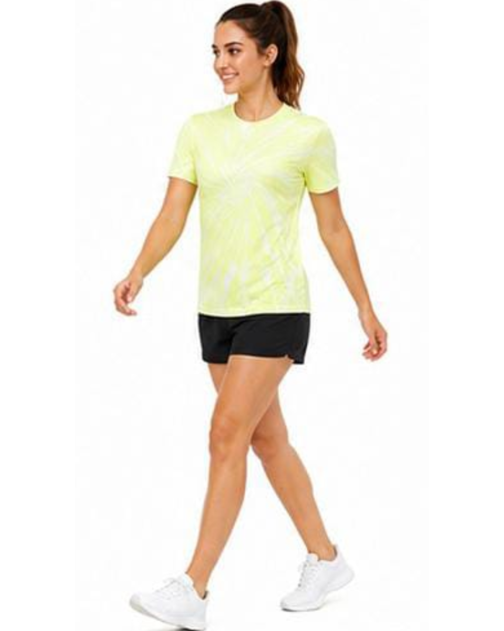 A woman modeling a short-sleeve athletic t-shirt in neon yellow with a white abstract pattern, paired with black athletic shorts and white sneakers, set against a plain white background.