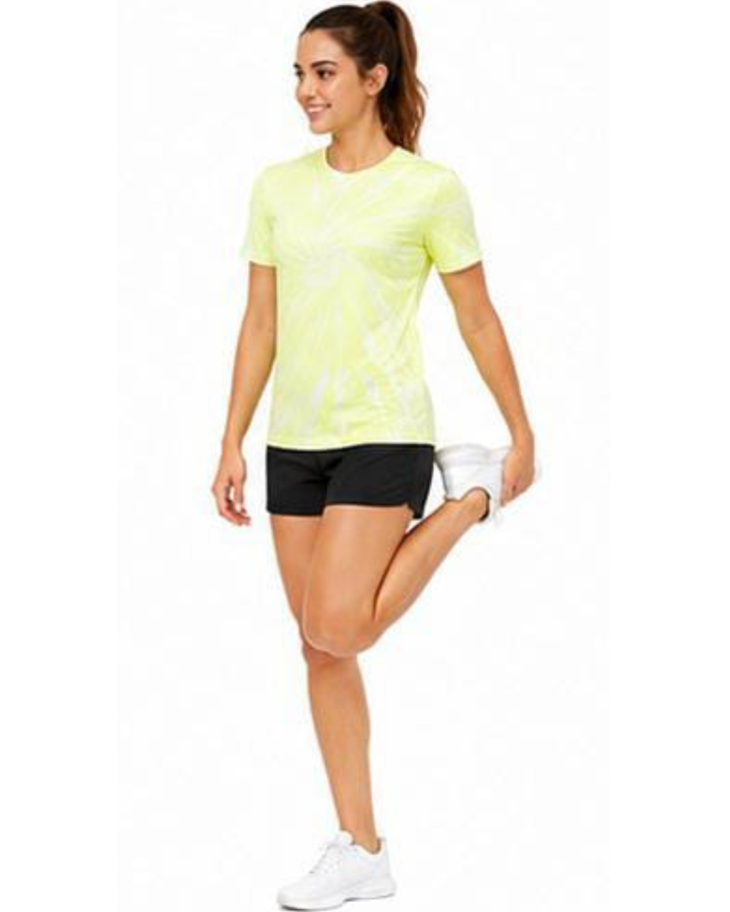 A woman modeling a neon yellow-green athletic t-shirt with a white abstract pattern, paired with black athletic shorts and white sneakers, performing a leg stretch against a plain white background.