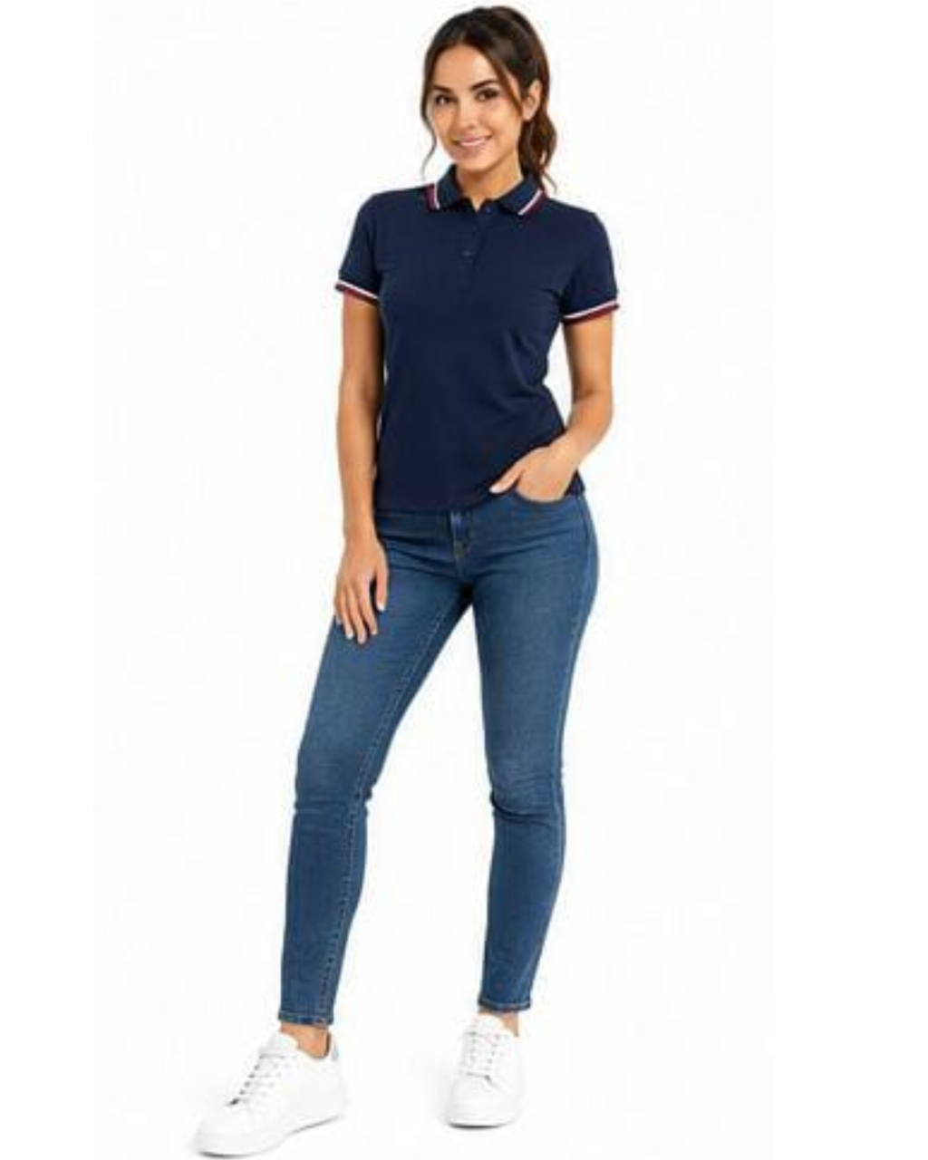 A woman modeling a navy blue short-sleeve polo shirt with white and red striped trim on the collar and sleeve cuffs, paired with blue skinny jeans and white sneakers, against a plain white background.
