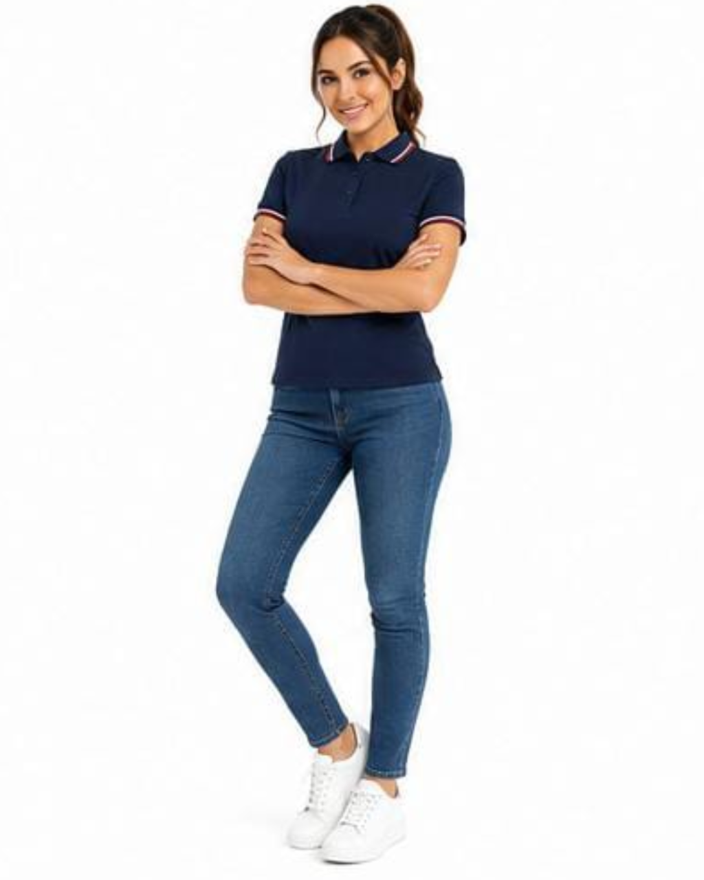A woman modeling a navy blue short-sleeve polo shirt with white and red striped trim on the collar and sleeve cuffs, paired with blue skinny jeans and white sneakers, against a plain white background.