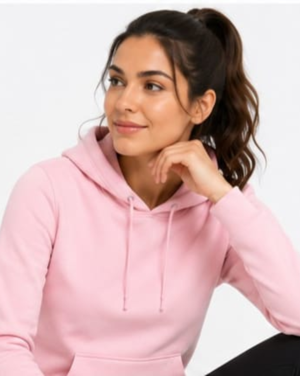 A woman with her hair in a high ponytail wearing a light pink pullover hoodie, posing against a plain white background.