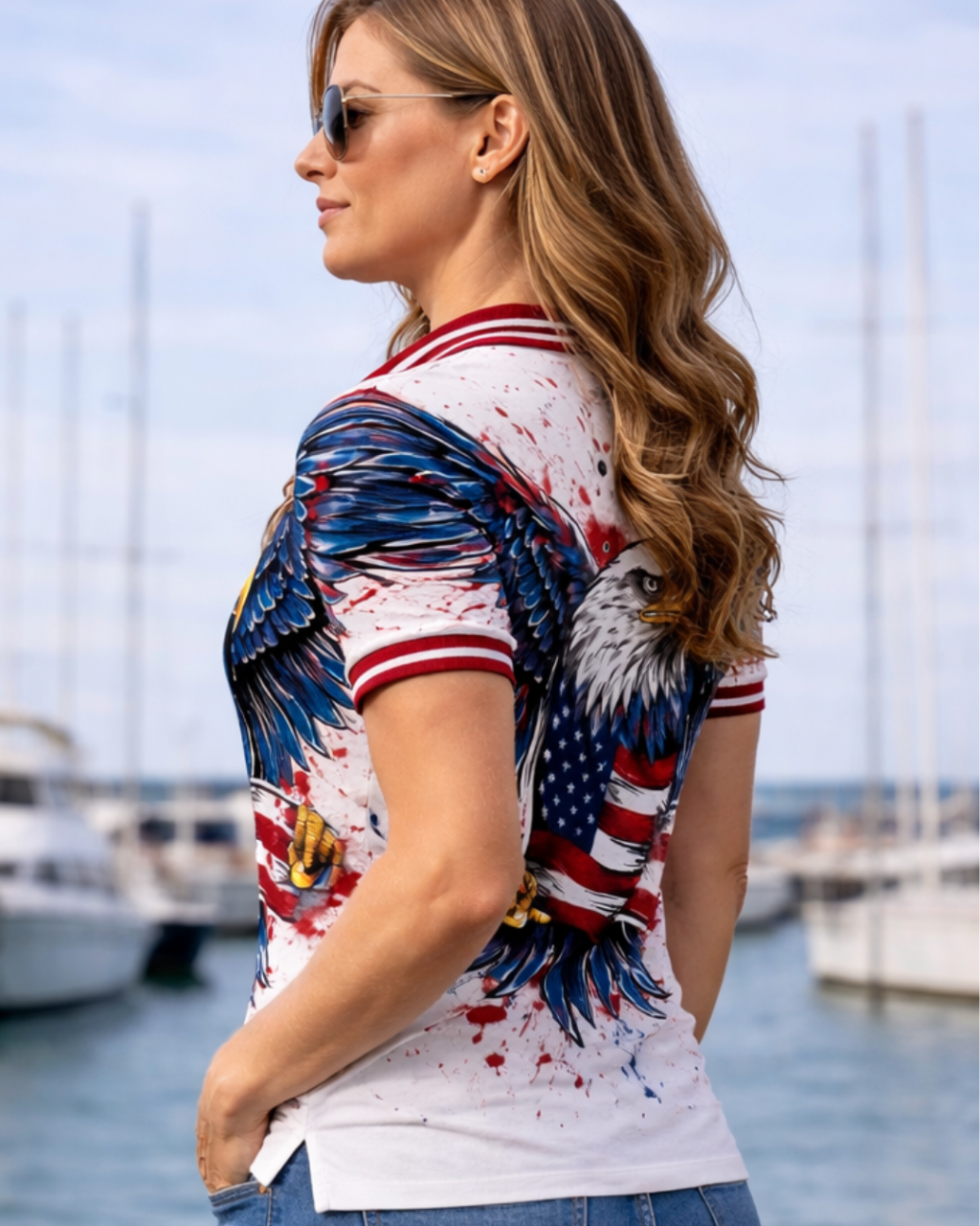 Woman wearing a colorful shirt with an eagle design by a marina.