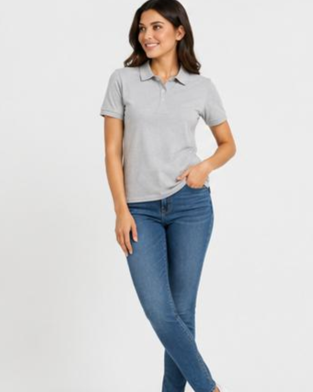 A woman modeling a light gray short-sleeve polo shirt paired with blue skinny jeans, standing against a plain light gray studio background.