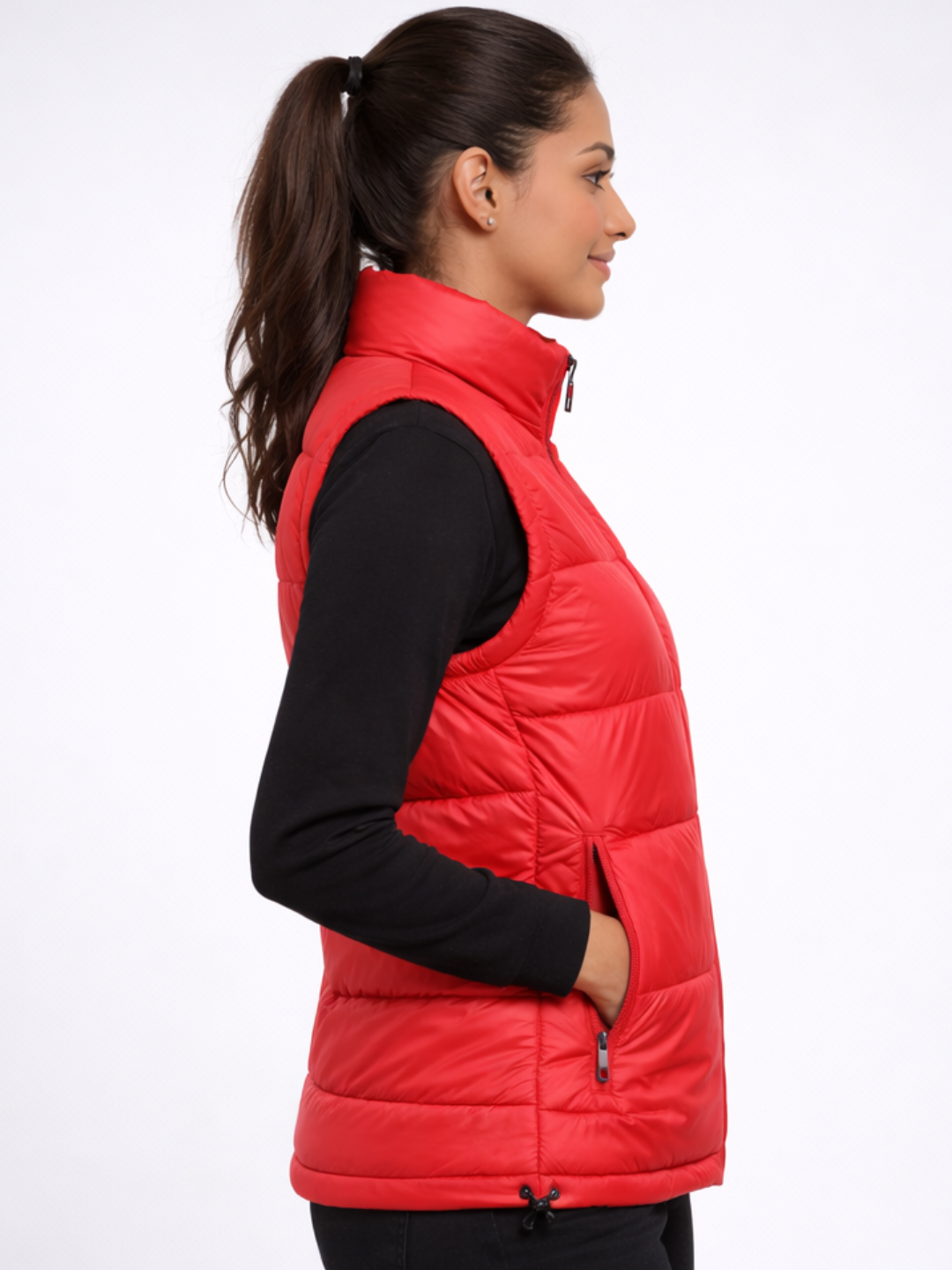 Woman wearing a red puffer vest over a black shirt on a white background