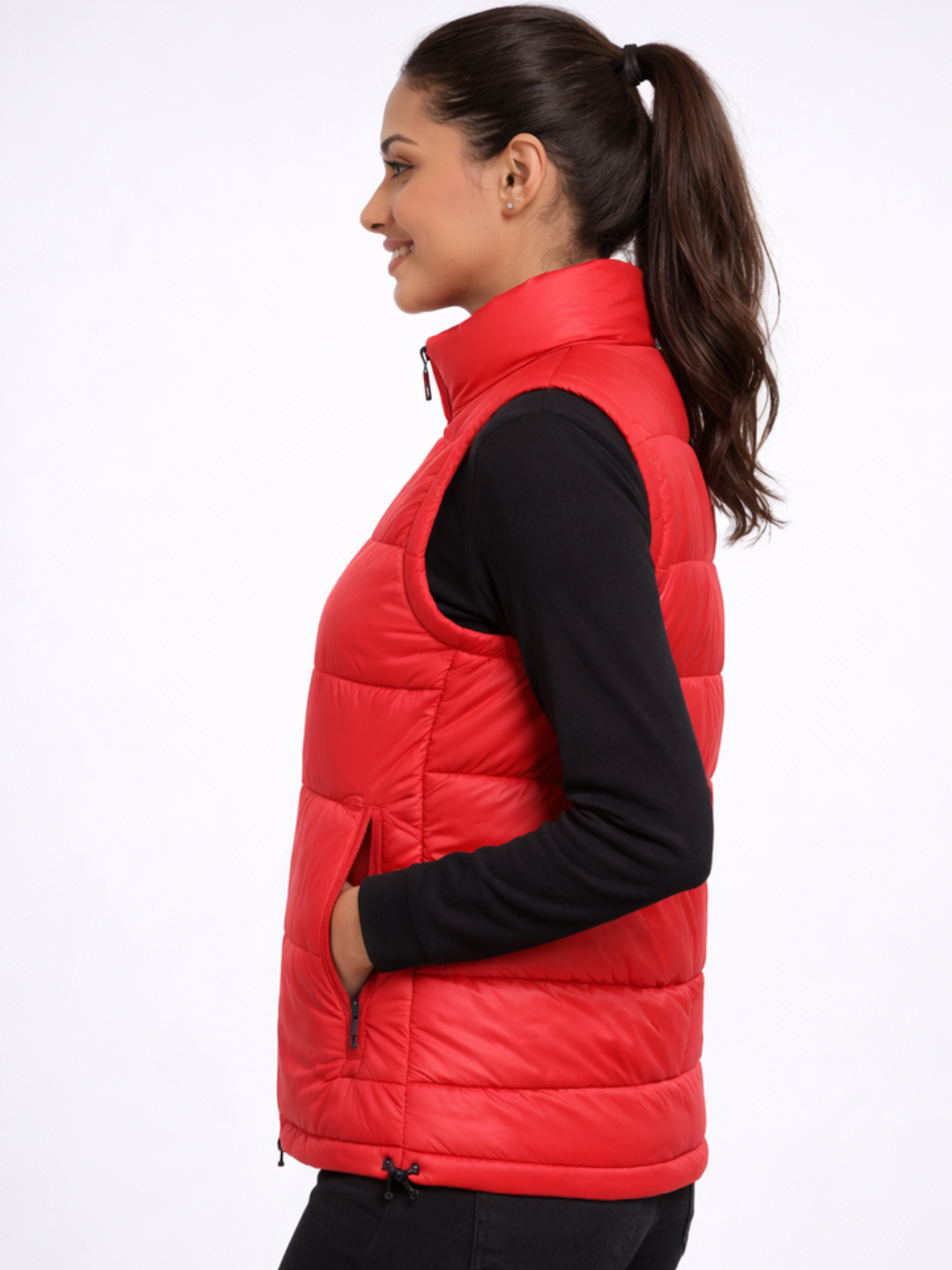 Woman wearing a red puffer vest over a black long-sleeve shirt on a white background