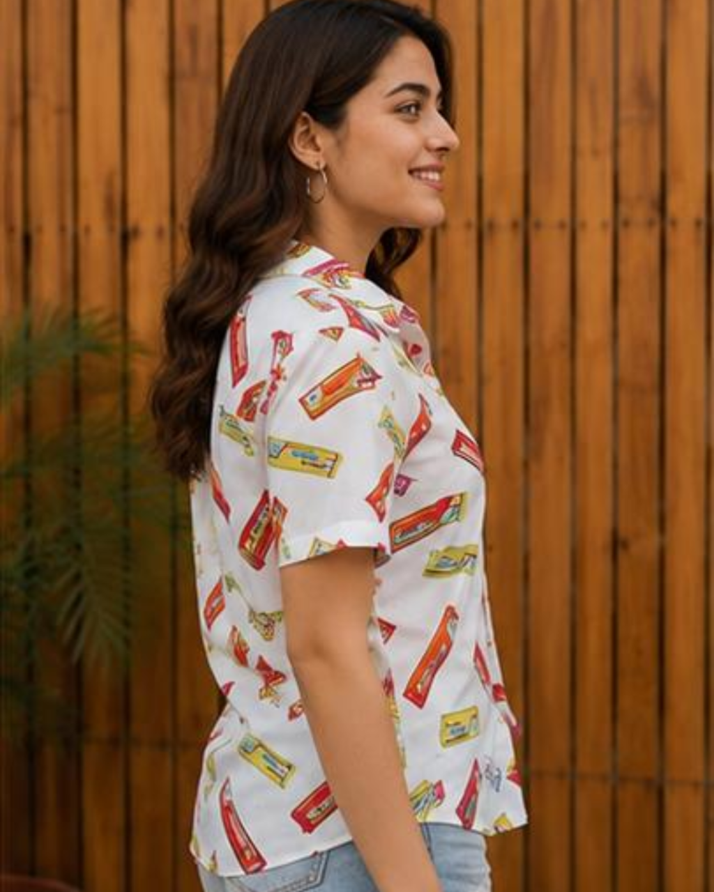 Woman wearing a white shirt with candy bar print against a wooden fence background
