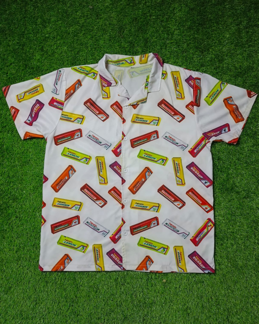 White shirt with colorful candy bar pattern on a green grass background