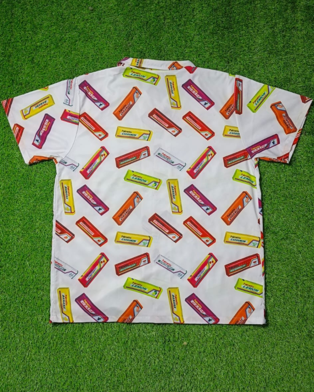 White shirt with colorful candy bar pattern on a green grass background