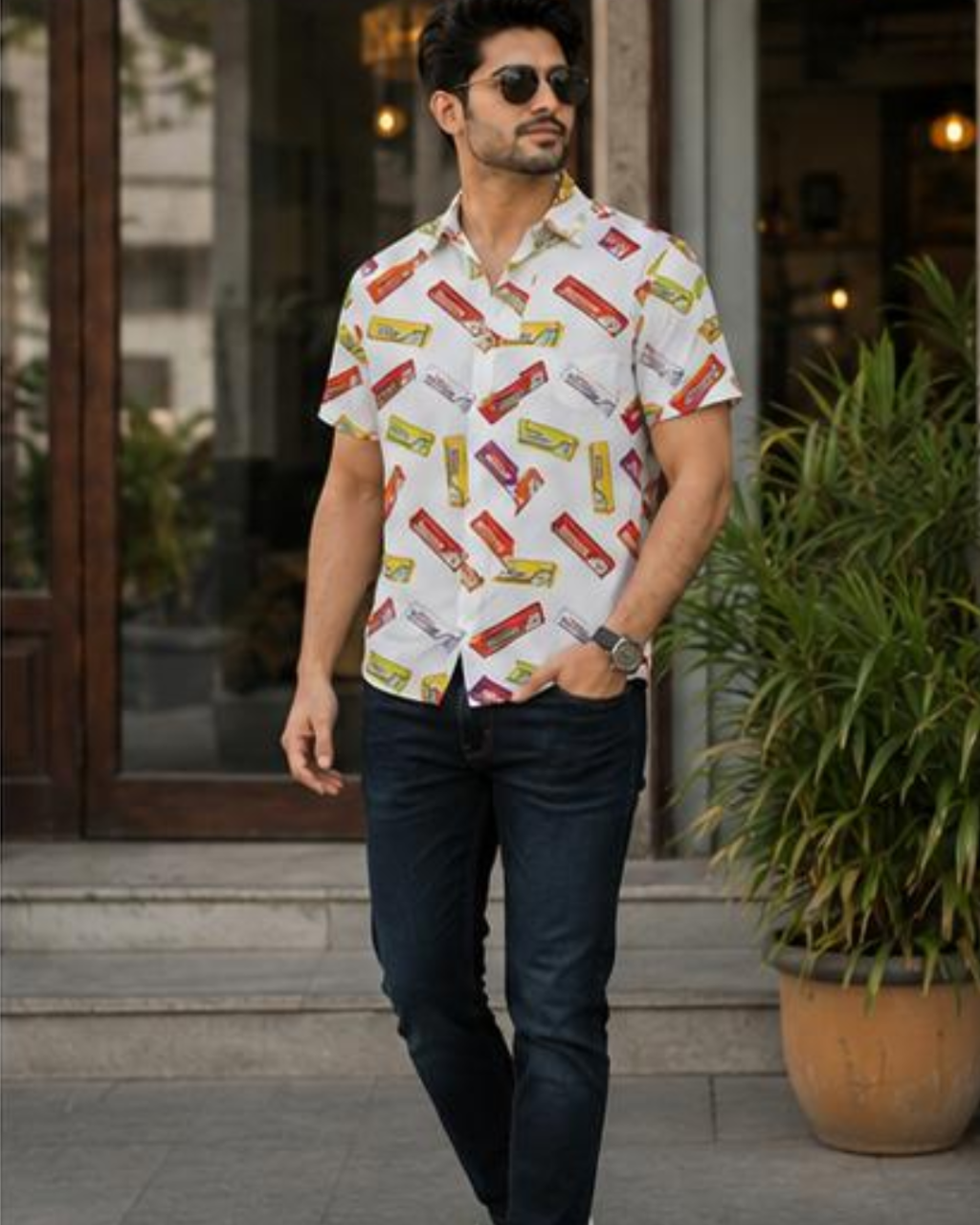 Man wearing a shirt with candy bar print walking outdoors.