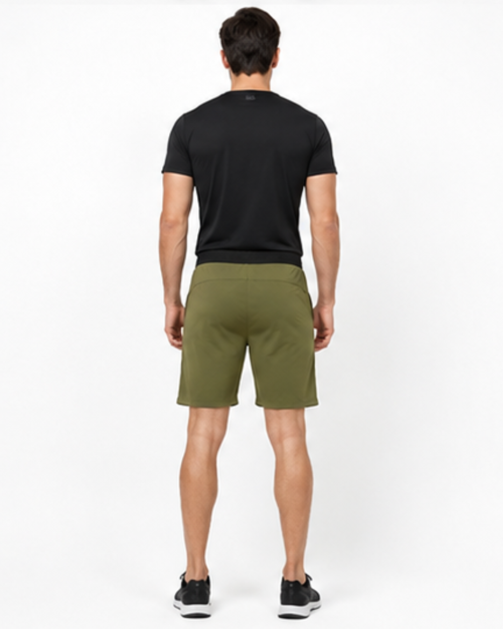 A man viewed from behind wearing a black short-sleeve athletic t-shirt and olive green athletic shorts, standing against a plain white studio background.
