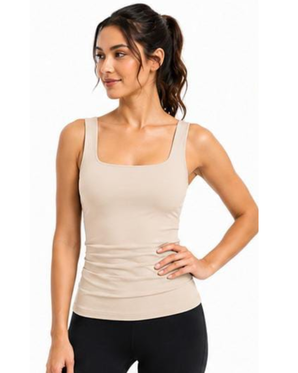 A woman modeling a beige ribbed tank top with a square neckline and wide straps, paired with black leggings, against a plain white background.