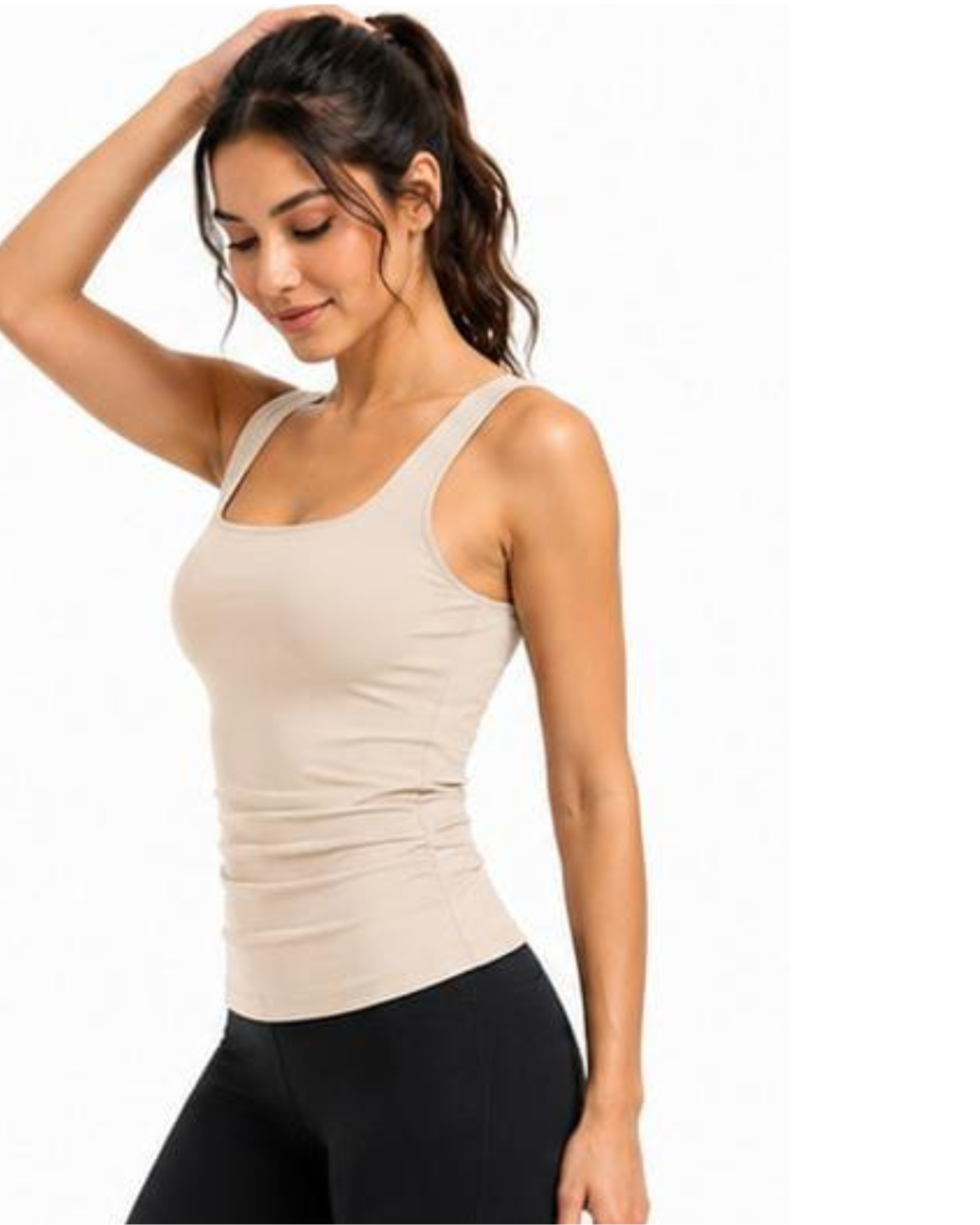 A woman wearing a beige ribbed tank top and black leggings, posing against a plain white background.