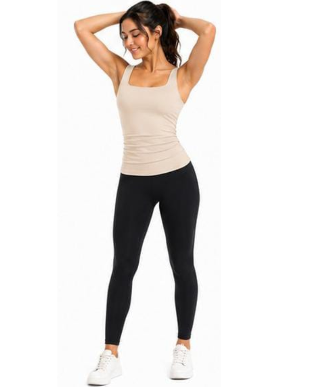A woman modeling a beige athletic tank top and black leggings with white sneakers, standing against a plain white background.
