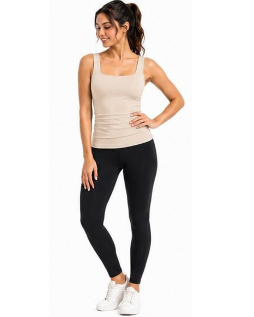 A woman modeling a beige ribbed tank top and black leggings with white sneakers, standing against a plain white background.