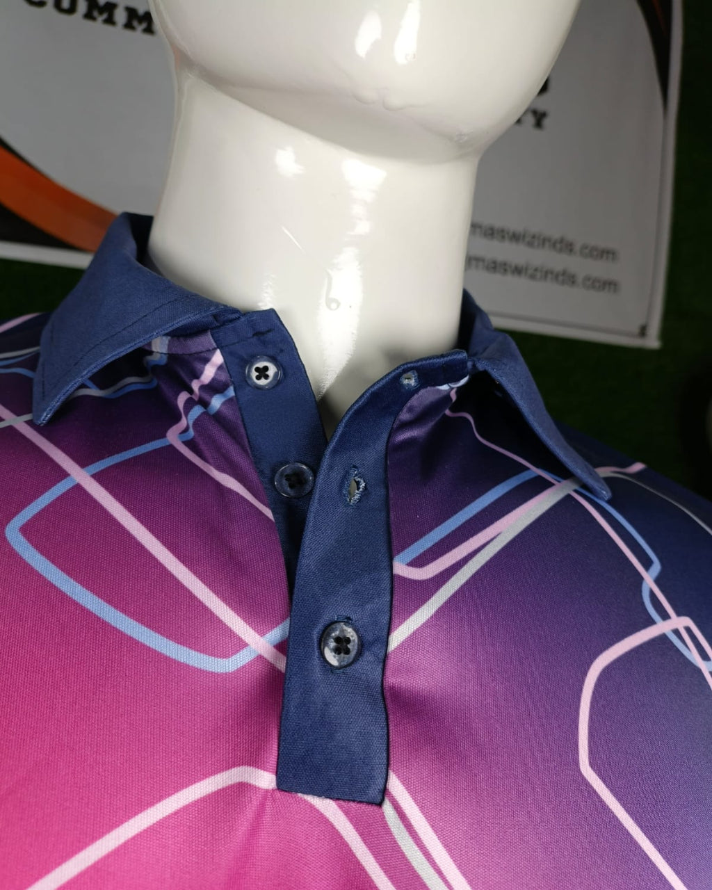 A close-up of a men's collared button-up shirt displayed on a white mannequin torso. The shirt features a vibrant magenta-to-purple gradient with abstract white and light blue geometric line patterns, paired with a solid navy blue collar and placket.