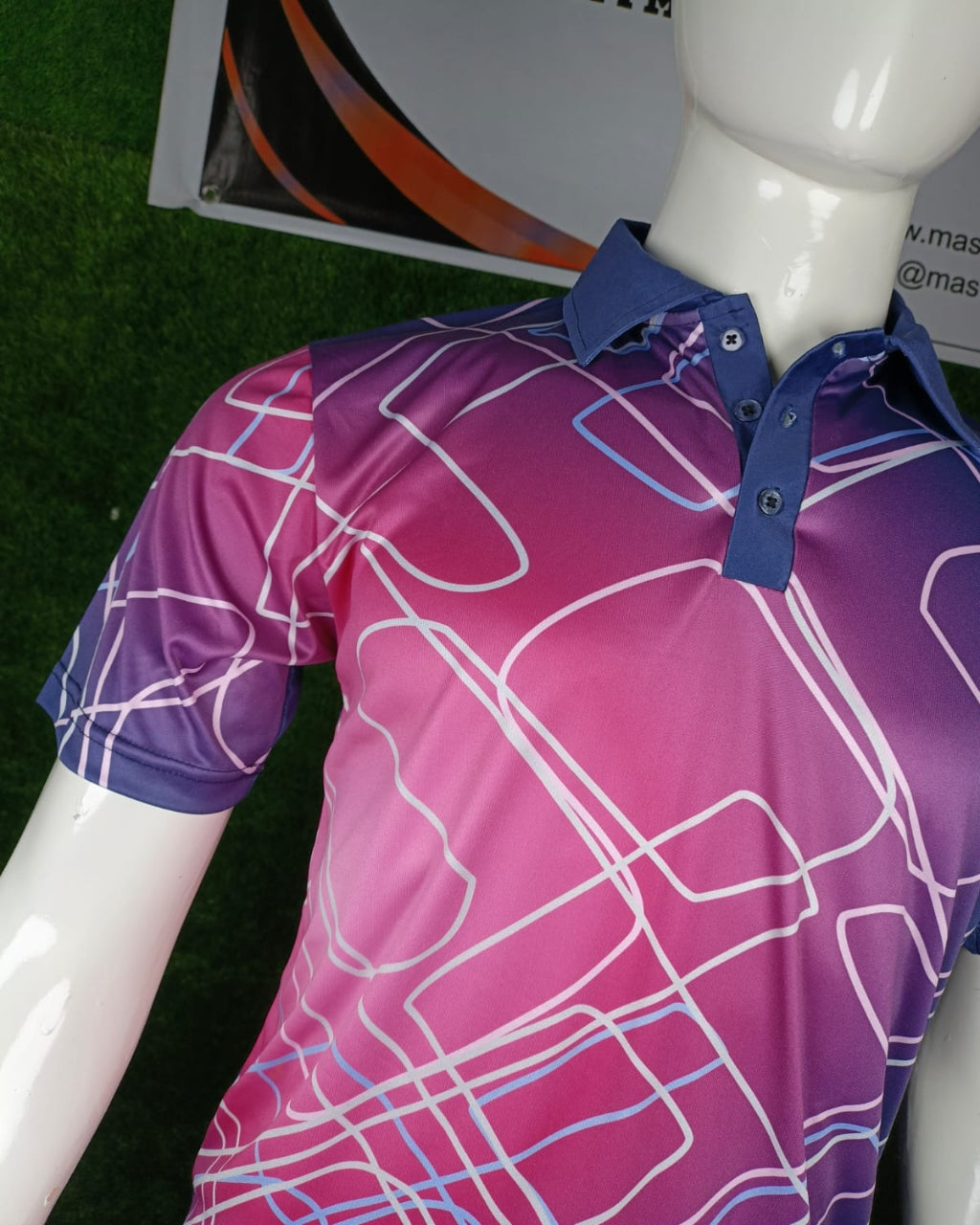 A short-sleeve polo shirt displayed on a white mannequin torso. The shirt features a vibrant magenta-to-purple gradient with an abstract white and light blue line pattern, and a solid dark blue collar and button placket.
