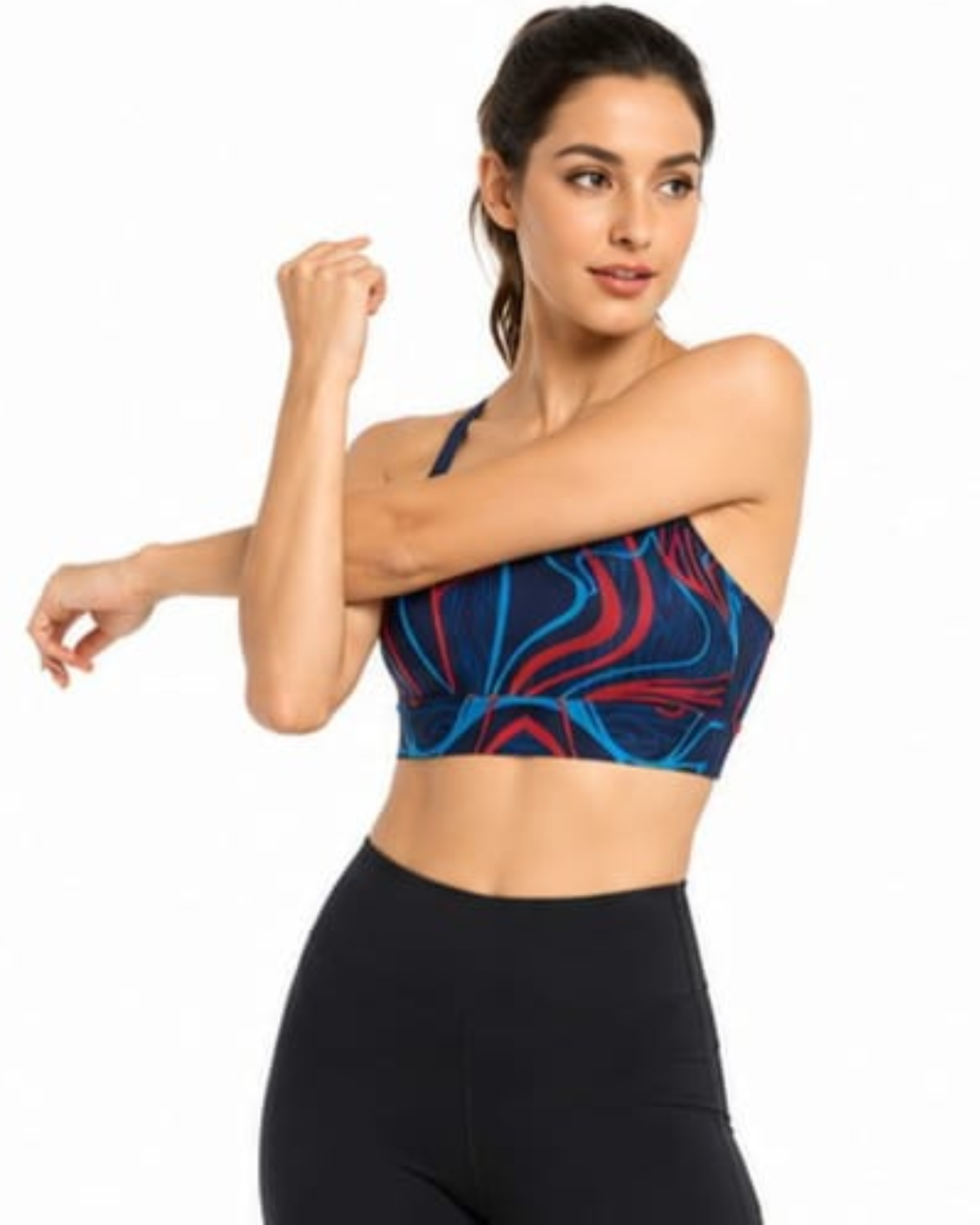 A woman modeling a sports bra with a blue, red, and black abstract swirl pattern, paired with black leggings, against a plain white background.
