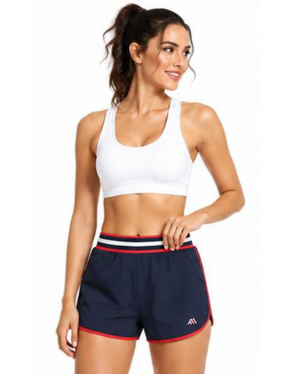 A woman modeling a white sports bra and navy athletic shorts with red and white trim, shown against a plain white background.