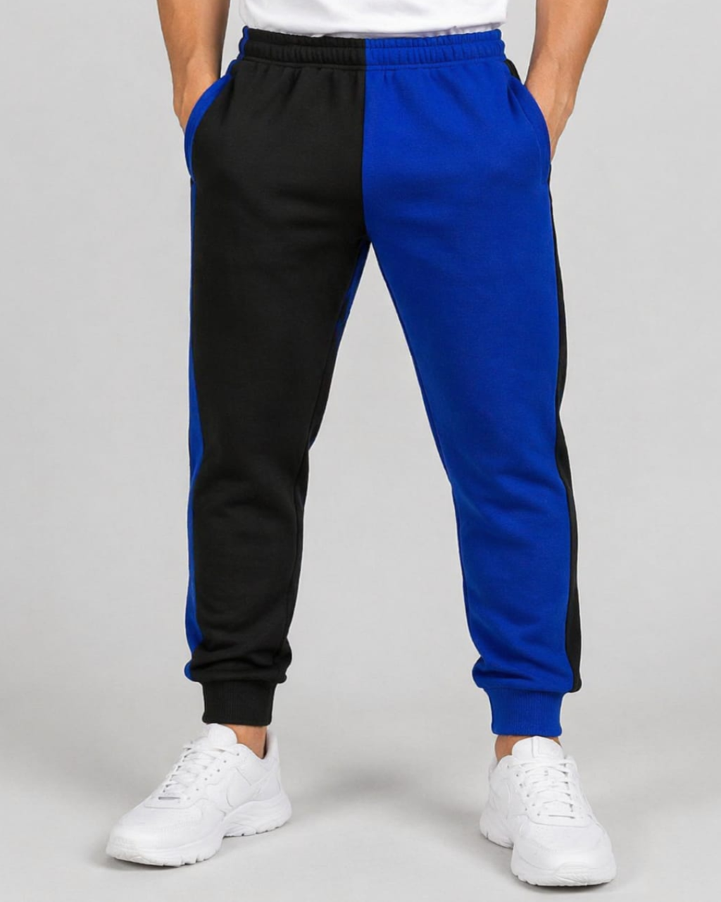 Black and blue jogger pants worn by a person on a gray background
