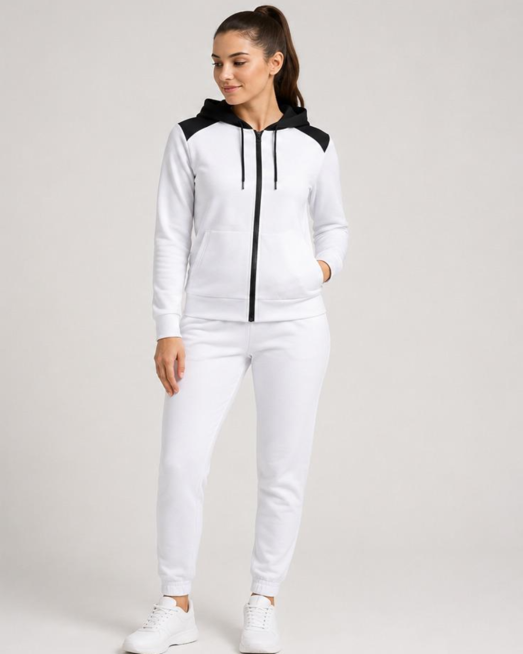 Woman wearing a white and black tracksuit on a plain background