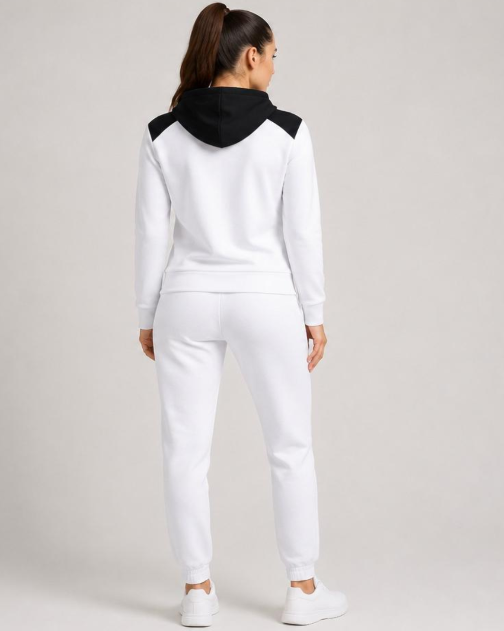 Person wearing a white tracksuit with black hood on a light gray background
