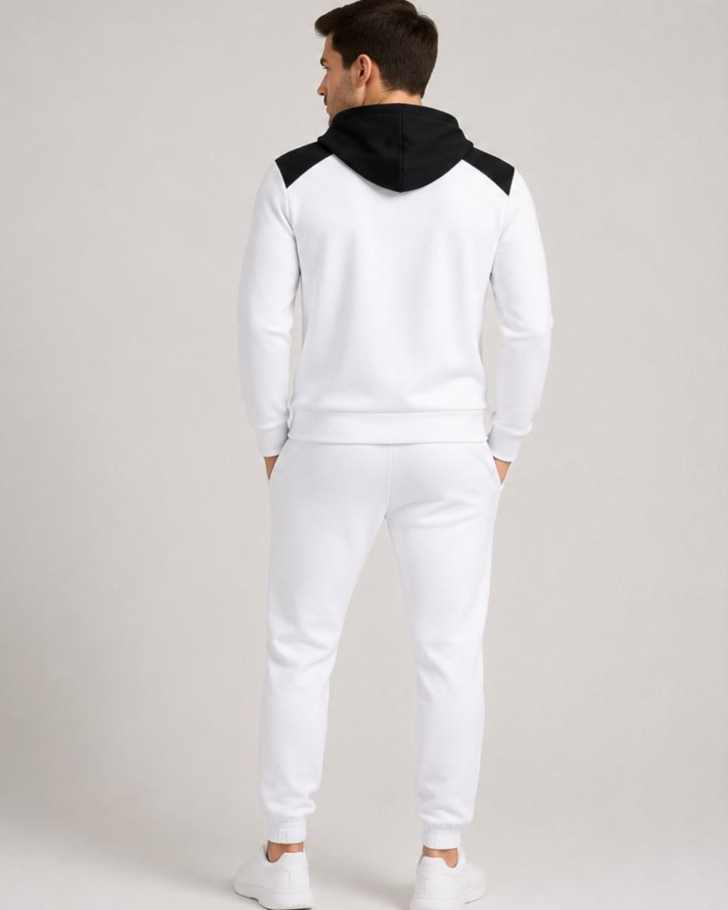 Person wearing a white tracksuit with black hood on a plain background