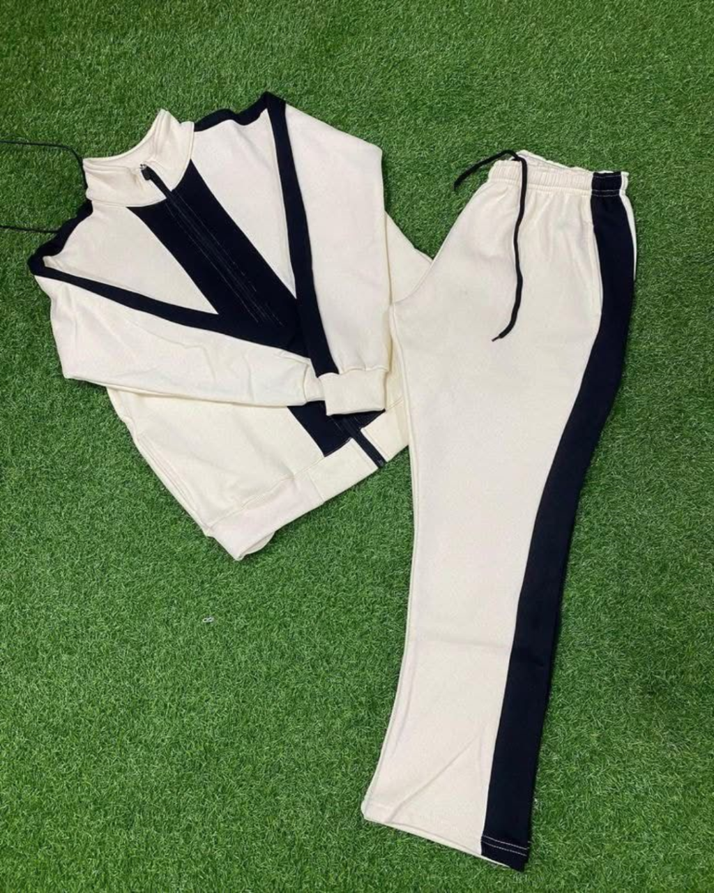 White tracksuit with black accents on a green grass background