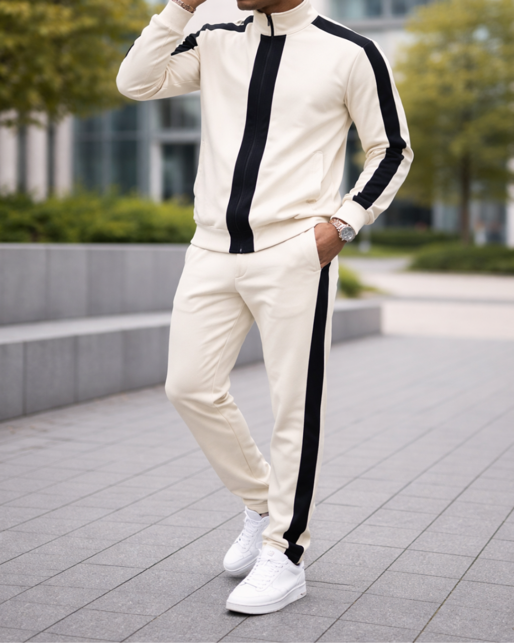 Person wearing a cream tracksuit with black stripes outdoors on a paved area.